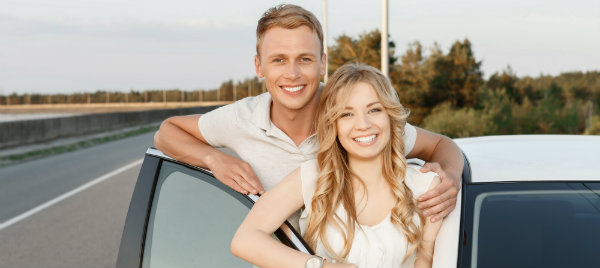 happy couple beside their white car