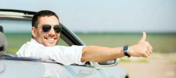 cheerful man driving a car and thumbs up